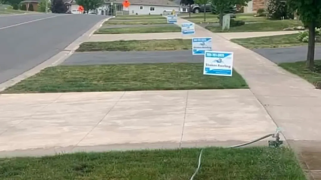 Several Stokes Roofing lawn signs along one residential street
